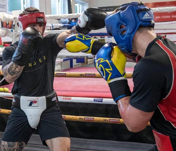 Two boxers fully equipped fighting at a boxing club